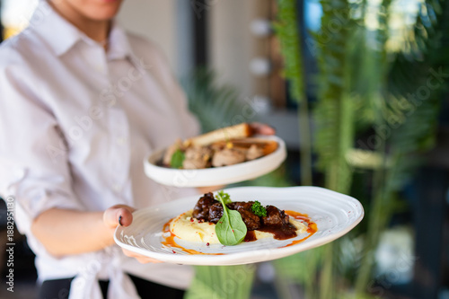 Foto A server presents two beautifully plated dishes in a restaurant setting, the for