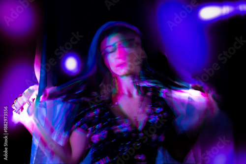 Billede på lærred Woman performing light painting, creating neon streaks of purple and blue light