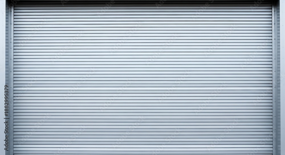 Fototapeta premium Closed gray metal security shutter door with horizontal slats and frame