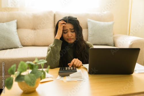 Foto Woman feeling stressed and anxious, calculating bills and taxes with a laptop an
