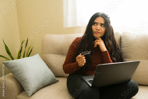 Bilde på lerret Woman thinking about online purchase with credit card, considering budget and on