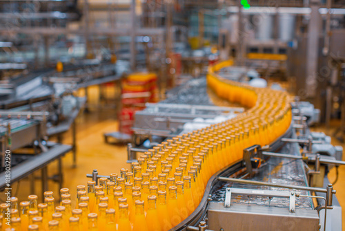 Beverage factory interior. Conveyor flowing with bottles for orange
