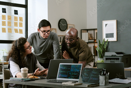 Cuadro en lienzo Multiethnic group of young adult men and man collaborating around laptops in mod