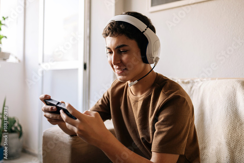 Teenager playing video game at home on sofa