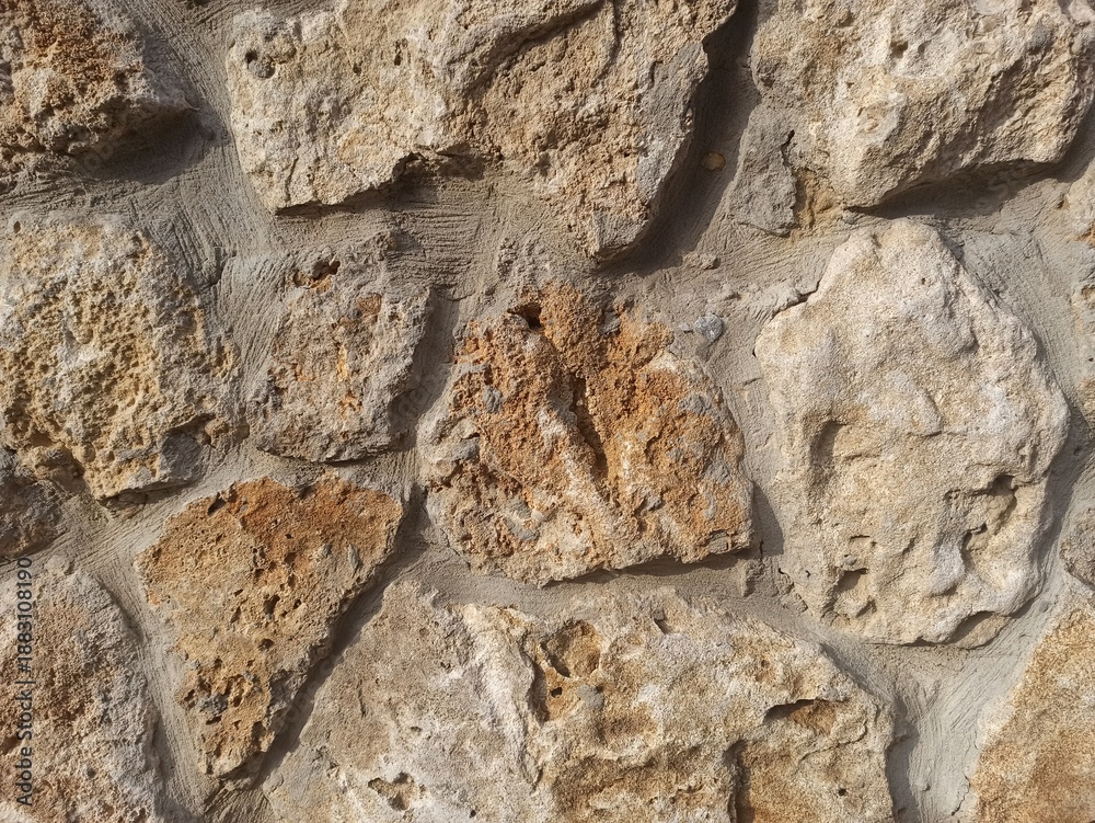 Fototapeta premium Rough natural stone wall texture with warm earthy tones