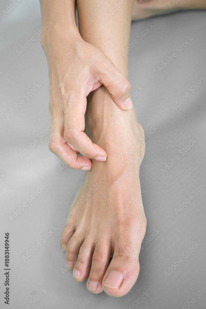 Fototapeta premium Close-up of female hands massaging her feet on grey background