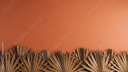 Dried palm leaves creating a natural border on a warm terracotta background with ample copy space.