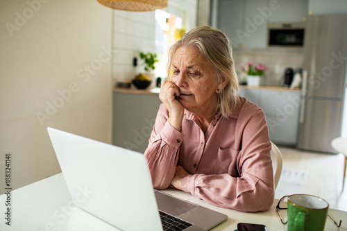 Cuadro en lienzo Senior woman worried at laptop in home kitchen
