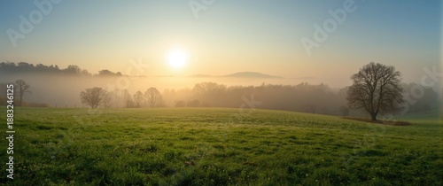 Autumn morning scene with foggy grassland, forest, and sky in the background