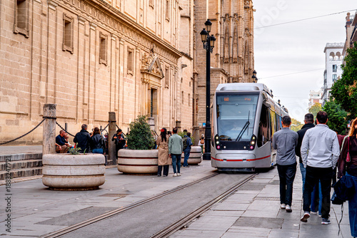 Cuadro en lienzo Tram is moving in front Cathedral Seville with tourists walking, life on streets Andalusian city