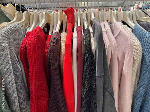 Fotografie Colorful knitted sweaters hanging on rack inside cozy clothing boutique
