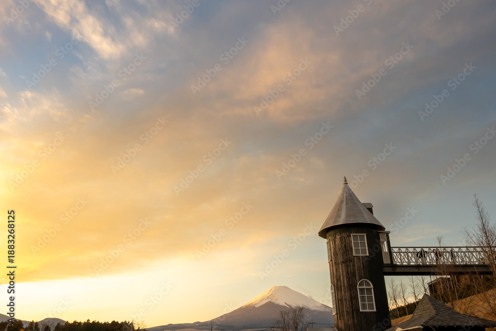 Fototapeta premium 夕日に染まる空と雪化粧した富士山とアンティークな塔の風景, 