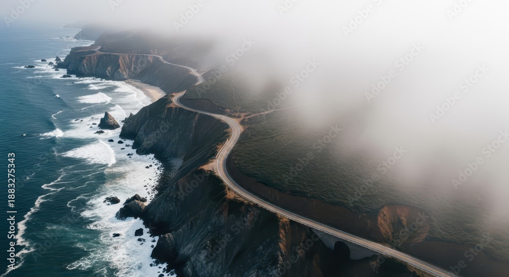 Fototapeta premium Elevated view captures winding coastal highway disappearing into thick atmospheric fog