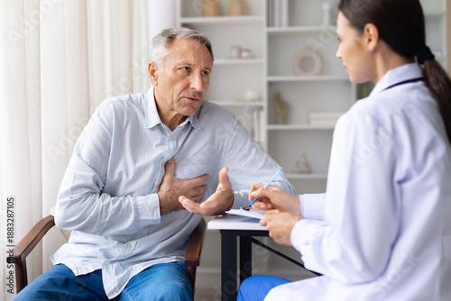 Senior male patient describing chest discomfort to female doctor during medical consultation, highlighting heart health and cardiovascular concerns