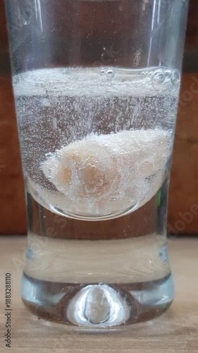 Tooth submerged in a glass of carbonating transparent liquid with many small bubbles