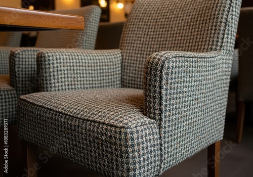 Comfortable upholstered armchair with houndstooth pattern sits beside a wooden table in an interior setting.