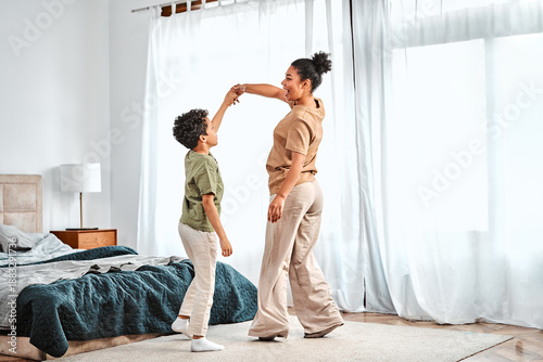 Fotografie Mother and son joyfully dancing at home, having fun and sharing happy moments together in a cozy interior