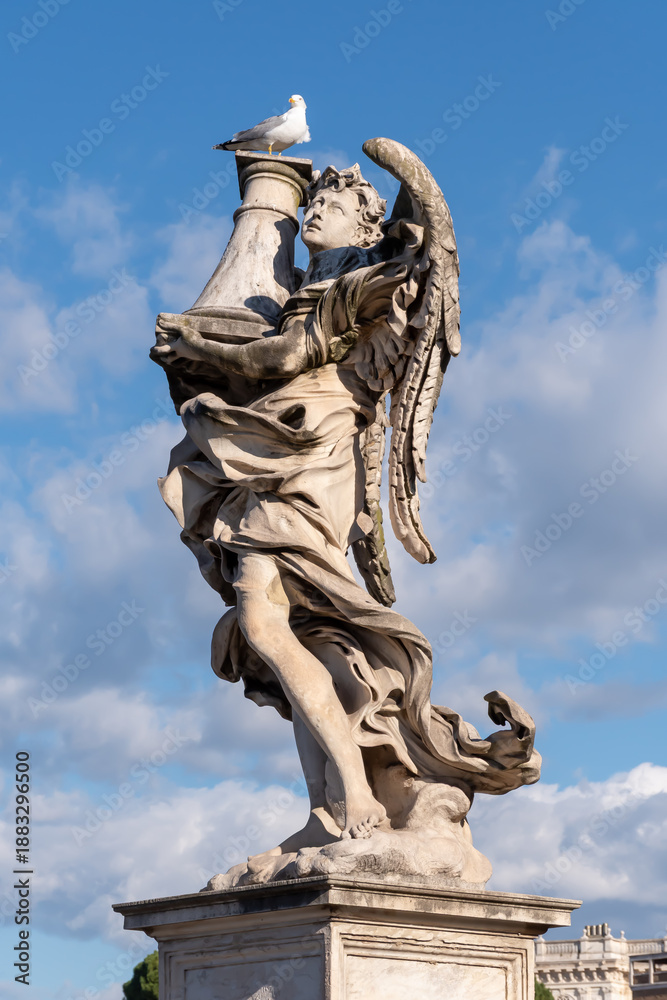 Obraz premium Seagull perched atop an angel statue in Rome, Italy, against a clear blue sky—classic marble sculpture blending wildlife, history, and timeless European art.