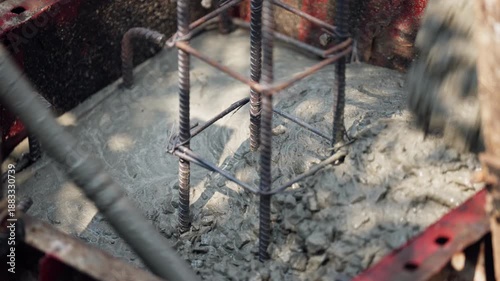 Wet concrete being poured into a reinforced steel rebar base, essential step in foundation construction, civil engineering concept.