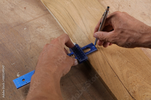 Εκτύπωση καμβά A hand uses a blue metal precision gauge and a silver mechanical pencil to mark