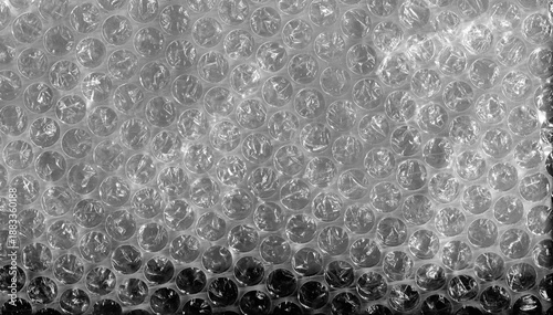 Transparent bubble wrap texture with soft reflected light. Plastic packaging material background, protective wrapping surface, abstract pattern, close up.