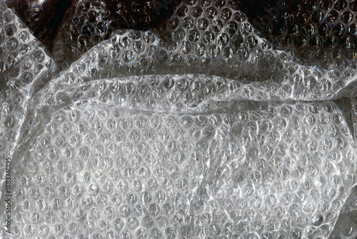 Transparent bubble wrap texture with soft reflected light. Plastic packaging material background, protective wrapping surface, abstract pattern, close up.