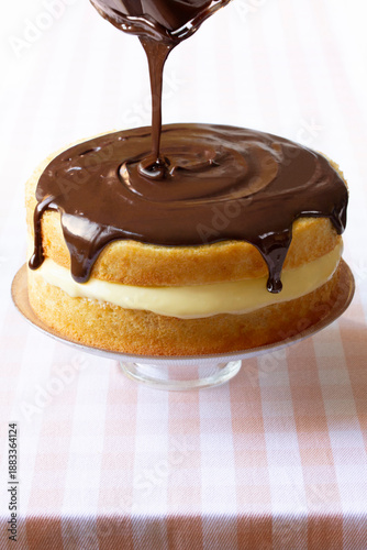 Boston Cream Pie on a cake stand with pink checkered tablecloth