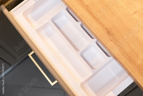 Open kitchen drawer with white plastic cutlery organizer.