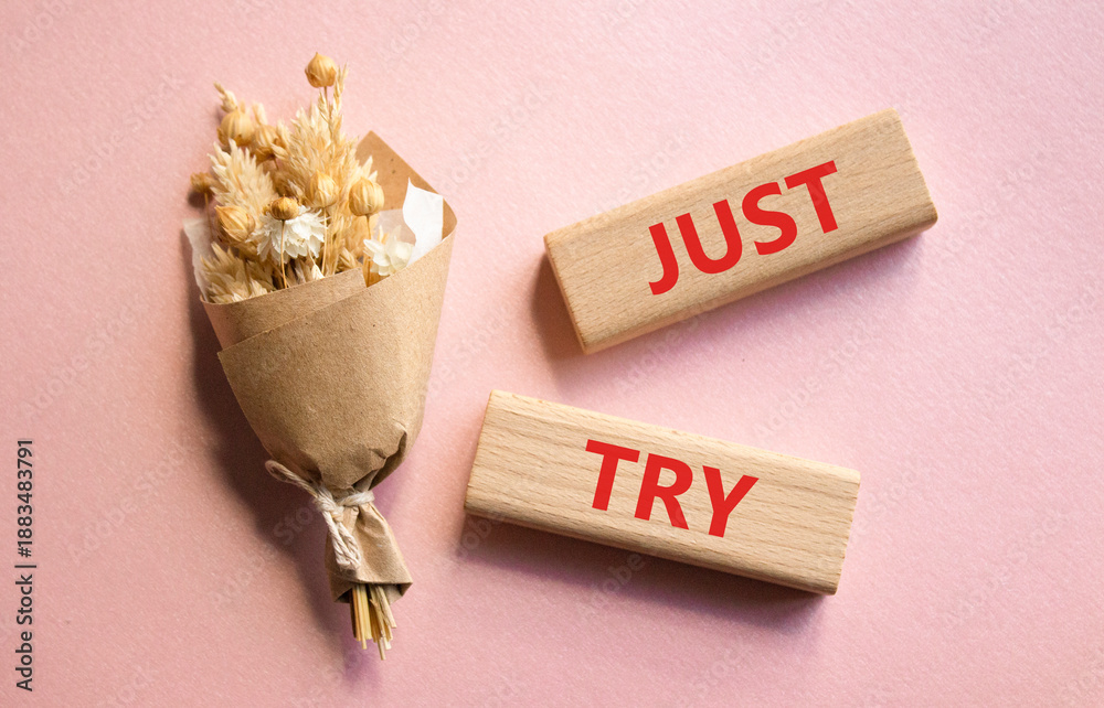 Fototapeta premium Just try symbol. Concept words Just try on wooden blocks. Beautiful pink background with bouquet of flowers. Business and Just Try concept. Copy space.