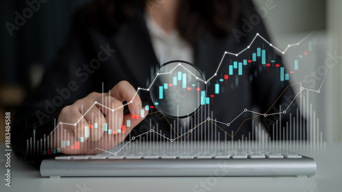 Obraz na plátne A business professional examines financial data using a magnifying glass over a keyboard, emphasizing accuracy and insight in a modern office environment