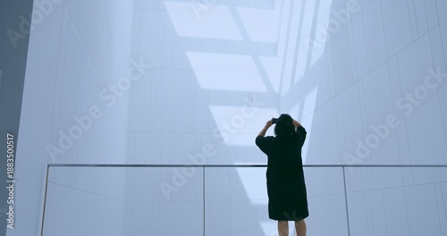 Billede på lærred Adult person photographing a striking abstract interior with a smartphone in a futuristic, minimalist building, representing contemporary design, digital capture, and urban exploration
