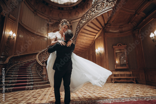 Couple dances together in grand building with elegant staircase during wedding ceremony