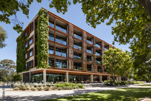 Modern building with green plants on the facade in bright daylight near a park setting showcasing outdoor seating arrangements