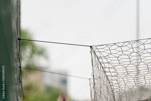 a soccer goal net tied to a green fence