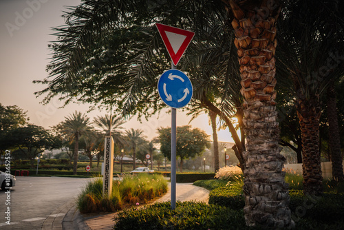 Bilde på lerret Traffic sign indicating yield and roundabout direction surrounded by palm trees