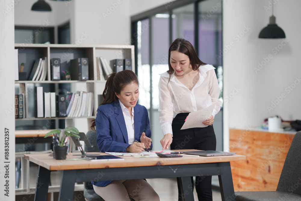 Fototapeta premium Asian businesswoman sitting at work using laptop talking and consulting in office 