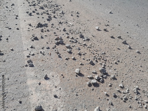 Gravel material spread on the asphalt surface of the road is very dangerous for road users passing by.