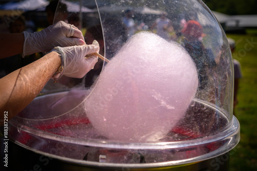 Hands spinning pink fairy floss at a country fair, giving a sense of whimsy and little kid excitement - horizontal