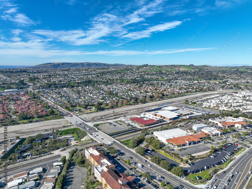Fototapeta premium Aerial view over San Juan Capistrano, California, featuring the historic mission, library, sports courts, and an Amtrak train pulling into the downtown station. High quality 4k footage
