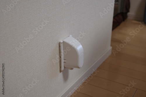 White plastic electrical outlet cover installed on a wall for child safety.