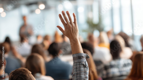 Meeting Question: A single hand raised high in a crowded conference setting. This photo captures the dynamic engagement within a corporate or academic assembly.