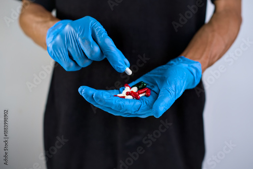 Φωτογραφία Hands in blue medical gloves hold assorted colorful pills, illustrating pharmace