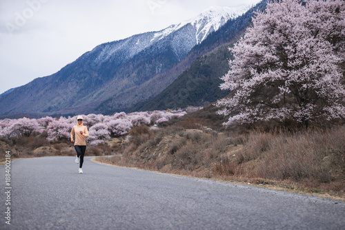 Fotografía Woman running in peach flowers blooming tibet, China
