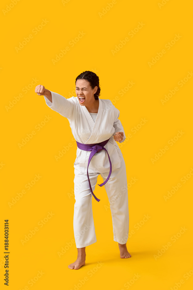 Obraz premium Young African-American woman practicing karate on yellow background