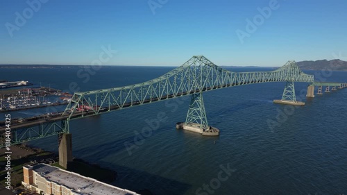 Aerial view of Astoria Megler Bridge spanning Columbia River in Oregon, showing steel structure, blue water, harbor area, and iconic Pacific Northwest transportation landmark.