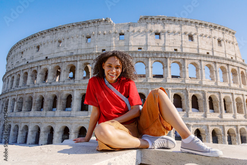 A cheerful woman poses at the Colosseum, showcasing Romes stunning architecture and vibrant culture, which create a memorable experience amidst the citys beauty and rich history