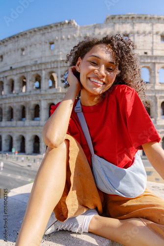 A cheerful woman poses with the magnificent Colosseum in the stunning background, showcasing her vibrant and colorful style, all while enjoying her wonderful visit to this iconic historic site