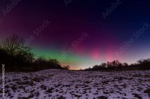 Colorful aurora borealis stretching across a starry winter night sky above snowy rural landscape in Silesia, southern Poland, 19.01.2026