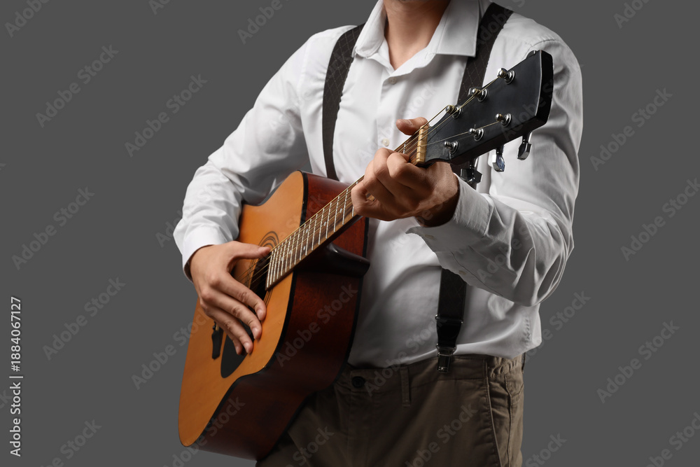 Naklejka premium Young man playing guitar on dark background