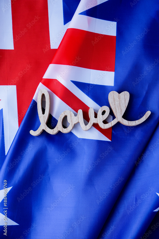 Fototapeta premium Wooden word LOVE on background of National symbol of Australia flag background. Copy space for your text. Concept of National day Independence